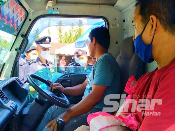 Hasanuddin (kiri) mendapatkan maklumat daripada pemandu kenderaan yang ingin merentas negeri.