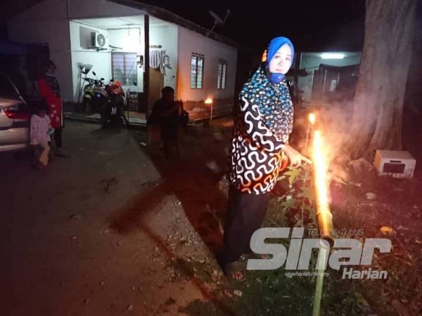 Kamsiah menunjukkan pelita buluh yang dihasilkan bersama suaminya.