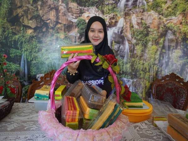 Nurul Atikah Radzi menunjukkan kek lapis masam manis yang ditempah pelanggan ketika tinjauan di rumahnya di Kampung Bubor, di sini yang juga air tangan ibunya.- Foto Bernama