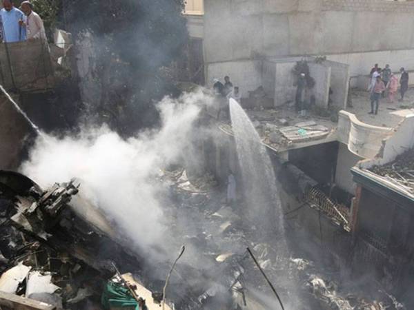 Bomba memadam bangkai pesawat yang terbakar selepas terhempas di kawasan perumahan di Karachi. - Foto: Agensi