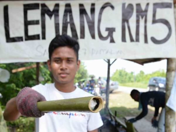 Pembantu Muhamad Azmi, Muhammad Syafeed Ali, 21 menunjukkan batang lemang yang sedia untuk dibakar di gerai mereka di Kampung Bukit Nambua, Kuala Nerang.