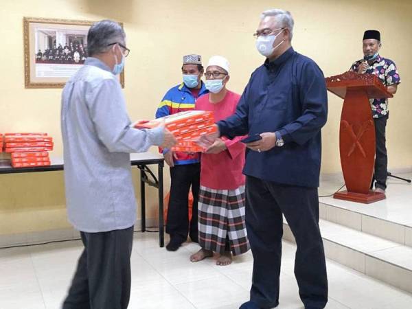 Noh (kanan) menyampaikan sumbangan kain jubah kepada salah seorang wakil masjid pada Majlis Penyampaian Sumbangan Anak Yatim Parlimen Tanjong Karang di Homestay Haji Omar Parit 2 di sini hari ini.