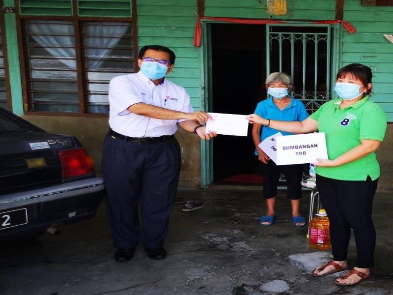 Seorang wakil Tenaga Nasional Berhad (TNB) (kiri) menyantuni golongan yang terjejas akibat wabak COVID-19 di Chuah, Negeri Sembilan. TNB turut menyampaikan bantuan daripada wakalah zakat kepada golongan bukan Islam yang layak seperti mereka yang berpendapatan rendah, orang kurang upaya (OKU), warga emas dan golongan B40.