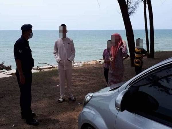 Anggota bertugas sedang memberi nasihat kepada salah sebuah keluarga yang ditemui sedang bersiar-siar di kawasan pantai Teluk Lipat, Dungun di sini semalam. - Foto Ihsan Facebook IPD Dungun