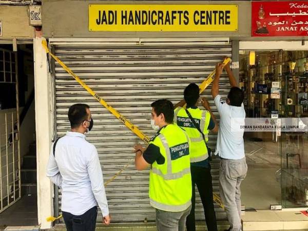 Anggota penguatkuasa DBKL menyita premis kedai milik warga asing berkenaan. - Foto ihsan Facebook DBKL