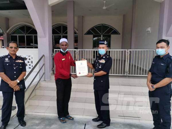 Barudin (kanan) menyampaikan surat penghargaan atas keberanian Nor Iman menyelamatkan mangsa kemalangan di Masjid Aziziah Batu 10, Hutan Melintang hari ini.