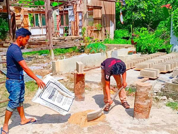 Muhammad Hakim Hakimi (kiri) dan Mohd Haizul Naimi memunggah pasir yang diambil dari sungai sejauh 250 meter untuk dijadikan sebagai bata.