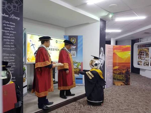 Dr Hasaan Basri menyerahkan skrol kepada robot yang mewakili pelajar, dalam simulasi yang diadakan. - Foto UniSZA