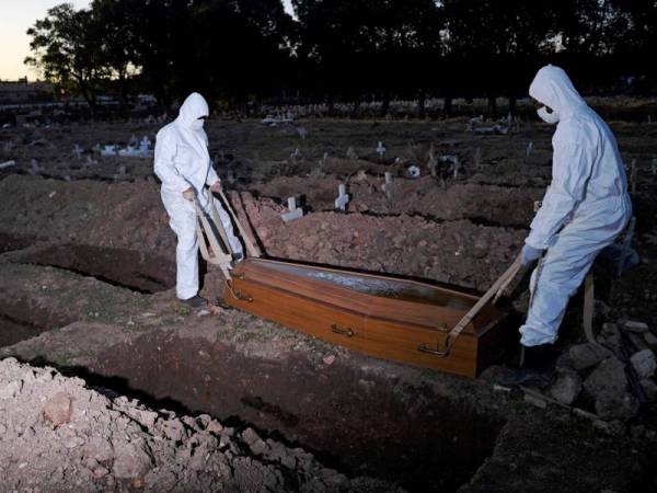 Petuga memakai pakaian pelindung menguburkan mangsa Covid-19 di tanah perkuburan Sao Franciso Xavier di Rio de Janeiro, Brazil. - Foto AFP