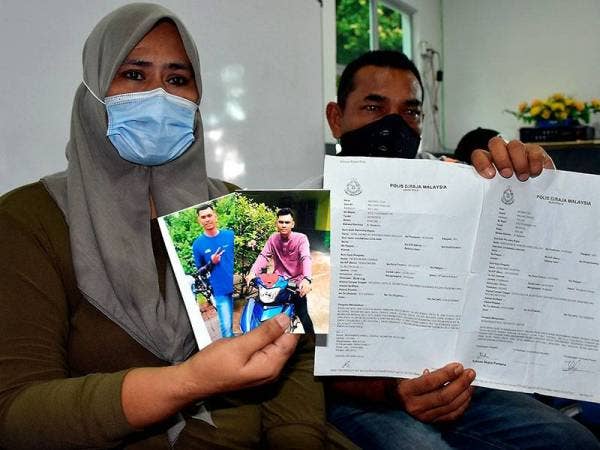 Asiah Basiron, 45, dan suaminya, Ab Rahim Yakub, 48, menunjukkan gambar Muhd Akmal Sharul Nizam, 22, dan laporan polis tentang kehilangan anaknya pada sidang akhbar hari ini. - Foto Bernama