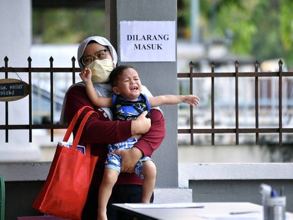 Pengasuh Nor Fashalna Mohd Azmi cuba menenangkan kanak-kanak Aidan Afham Ahmad Syahir ketika hadir di Taska Permata DD hari ini.