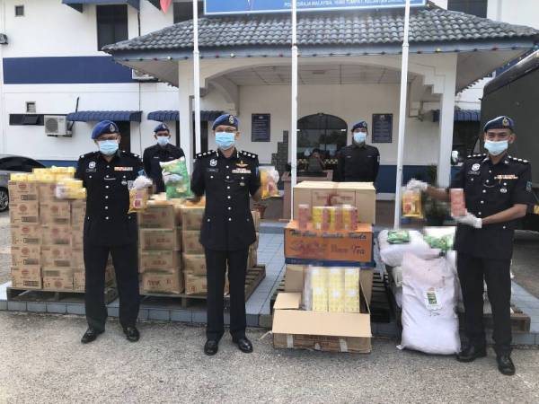 Norzaid (tengah) bersama barisan pegawai dan anggota dari PPM Wilayah Tiga Pengakalan Kubor Tumpat menunjukkan minyak masak dan teh yang diseludup dan diletakkan di sebuah stor yang dijadikan transit di Nibong, Tumpat.