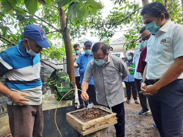 Ahmad (tengah) mencuba madu kelulut ketika beliau melawat kebun madu kelulut di Kampung Permatang dekat Kuantan semalam.