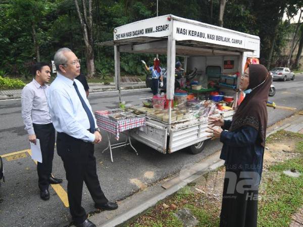 Annuar (kiri) bertemu dengan Cik Nah untuk menyerahkan lesen niaga hari ini.