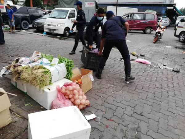 Anggota penguat kuasa menyita barangan milik penjaja warga asing di luar Pasar Borong Kuala Lumpur.