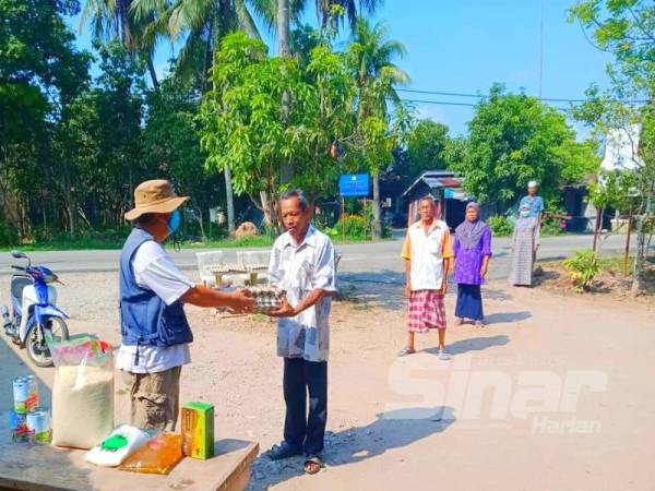 Nor Alam (kiri) menyerahkan sumbangan kepada golongan yang memerlukan hasil keuntungan jualan kedai serbaneka KRT Banggol Perdana.