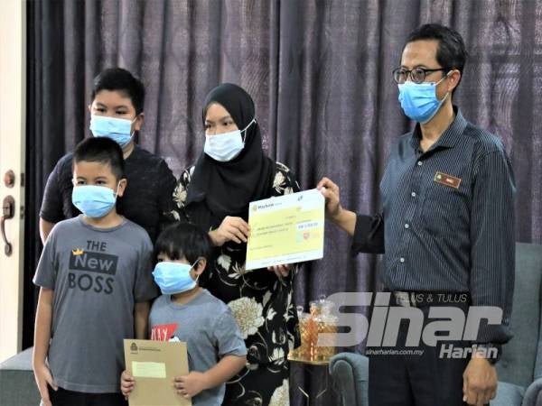 Mohammad Ramli (kanan) menyampaikan FPM dan pencen penakat kepada Sharanizawati di rumahnya di Sungai Buloh, kelmarin.
