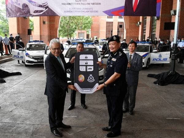 Menteri Dalam Negeri, Datuk Seri Hamzah Zainuddin (dua dari kiri) menyerahkan replika kunci kepada Abdul Hamid simbolik penyerahan kenderaan peronda baharu PDRM hari ini. Foto: Bernama