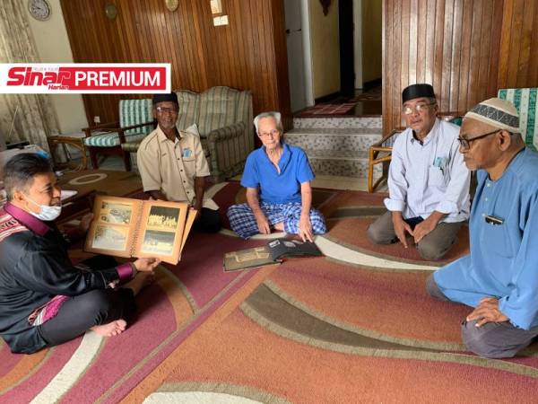 he Hamid (tengah) menunjukkan gambar lamanya ketika menentang Filipina pada tahun 1960 ketika menerima kunjungan di rumahnya.