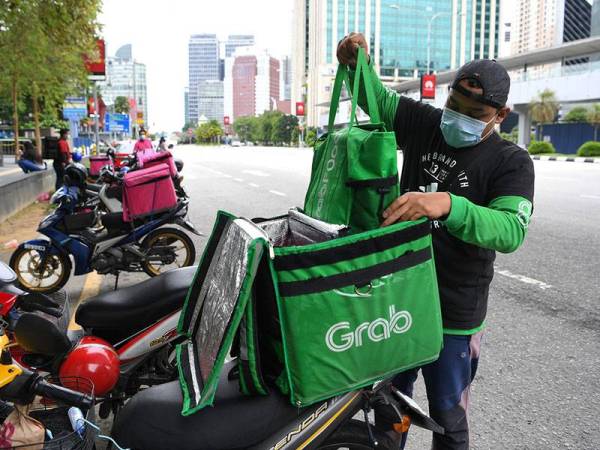 Rakan Penghantar Makanan Firdaus Ghazali memasukkan makanan sebelum menghantar pesanan tersebut kepada pelanggan ketika tinjauan di sekitar ibu kota hari ini.