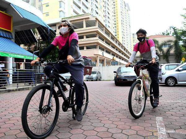 Rakan Penghantar Makanan Muqriz Rahman (kiri) dan Mak Sai Kam memulakan tugas bagi menghantar pesanan makanan kepada pelanggan ketika tinjauan di sekitar ibu kota hari ini.