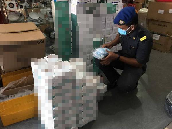 Anggota penguat kuasa memeriksa harga topeng muka yang dijual di sebuah di premis Pekan Kuah.