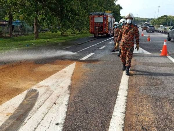 Anggota bomba melakukan operasi pembersihan akibat tumpahan minyak diesel petang tadi. Foto JBPM