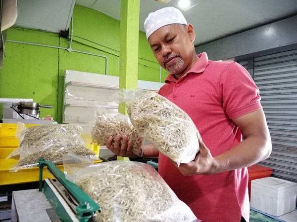 Rasdi menunjukkan ikan bilis mata biru yang siap dibungkus yang ditempah pelanggan.