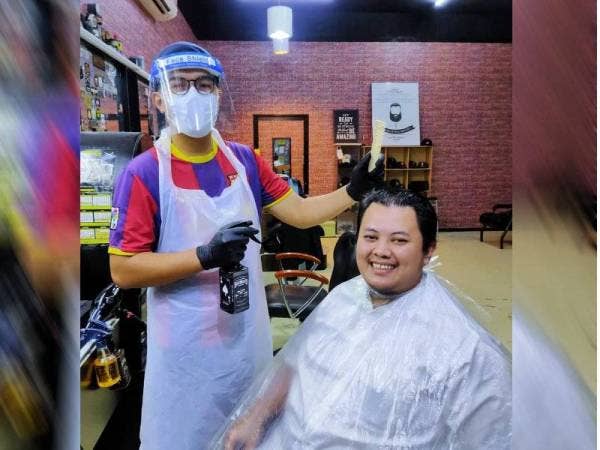 Mohamad Iqbar bersama pelanggan yang datang mendapatkan perkhidmatan guntingan sempena hari pertama kebenaran beroperasi, hari ini.