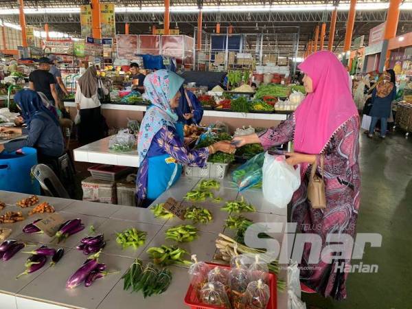 Sabariah (kiri) sentiasa memastikan penjarakkan sosial dilakukan semasa berinteraksi dengan pengunjung.