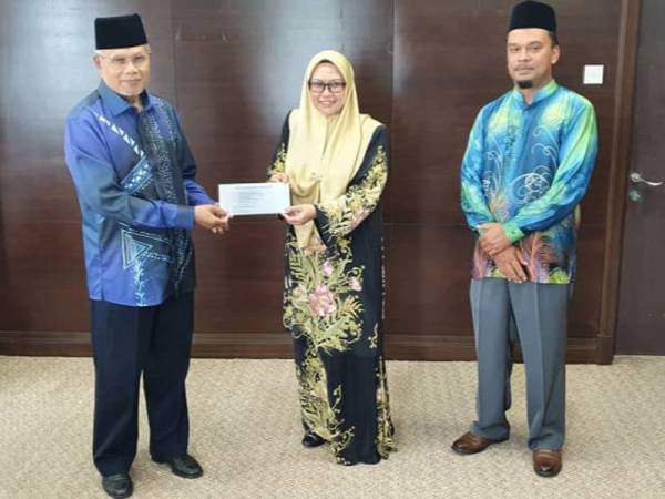 Najmi (kiri) menerima cenderahati daripada Sharifah Norulasyikhah di Wisma Darul Aman hari ini.