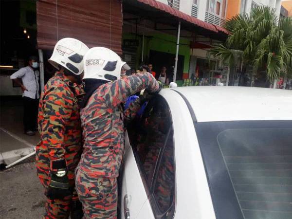 Anggota bomba menggunakan peralatan khas membuka pintu kereta bagi menyelamatkan kanak-kanak perempuan yang terperangkap di Bandar Sri Impian Kluang hari ini.
