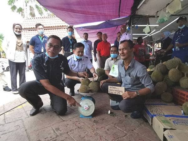 Rosol (kiri) menunjukkan bacaan pada alat penimbang ketika meninjau harga raja buah itu di Pasar Payang, hari ini.