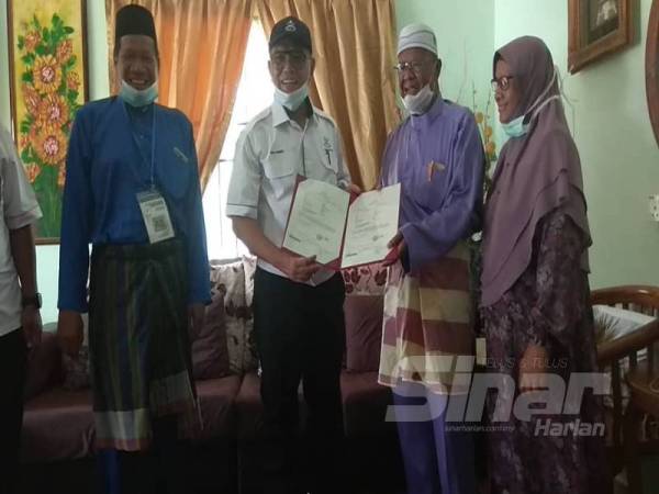 Suahilai (dua dari kiri) dan isterinya, Juaitar menerima kunjungan Wan Rosdy (dua dari kiri) bagi menyampaikan sendiri geran tanah milik peneroka itu. 