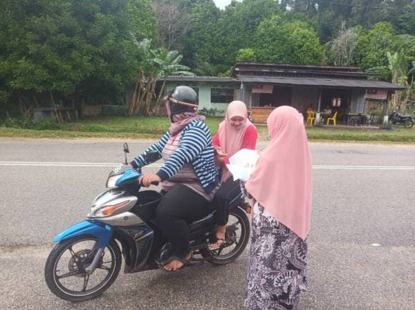 Guru SMK Kijal menyerahkan modul pembelajaran kendiri secara pandu lalu kepada murid yang hadir. 