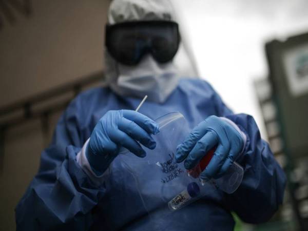 Pekerja kesihatan mengambil sampel ujian Covid-19 pandu lalu. Foto: Xinhua