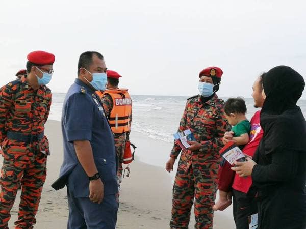 Mohd Khairiri (dua dari kiri) memberikan nasihat keselamatan kepada pengunjung Pantai Pandak.
