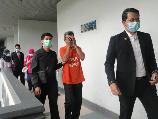 Bekas Setiausaha Kerja Eksekutif MPNM menutup muka ketika keluar dari Mahkamah Majistret Ayer Keroh di sini hari ini