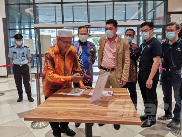 Ariffin melakukan proses imbas pada Kod QR yang disediakan sempena Majlis Perlancaran Sistem Masuk.la di Kuala Terengganu City Centre (KTCC) Mall di sini hari ini. 