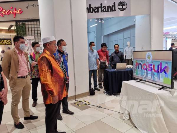 Ariffin (tengah) ketika merasmikan sistem Masuk.la yang dibangunkan bagi merekod kehadiran pengunjung di setiap premis di negeri ini hari ini.