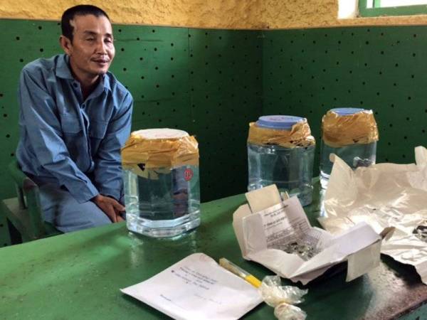 Truong Van Son (kiri) dan batu meteor palsu yang disimpan di dalam balang di balai polis Dong Thap, Vietnam baru-baru ini. - Foto Polis Dong Thap