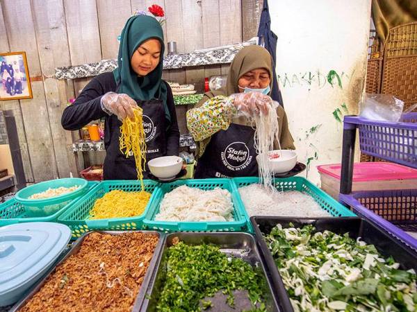 Isteri kepada pemilik kedai makan Station Mok Aji Niriezah Awang (kanan) bersama pembantunya Suryati Mohd Fauzi ketika melayan pelanggannya di kedainya di Kampung Delima di sini. -FOTO: BERNAMA