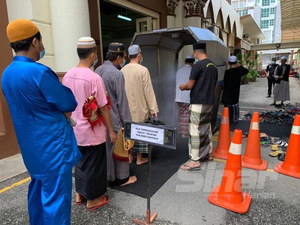 Jemaah perlu melalui terowong sanitasi sebelum masuk ke dalam masjid 