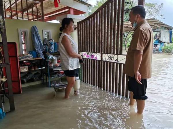 Jeck Seng (kanan) meninjau keadaan banjir di sekitar Pekan Nanas.