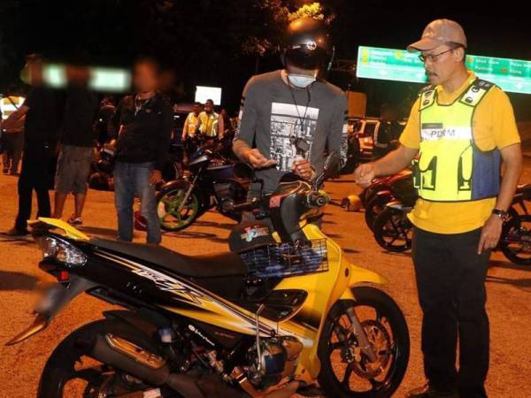 Azman membuat pemeriksaan ke atas penunggang motosikal yang ditahan.