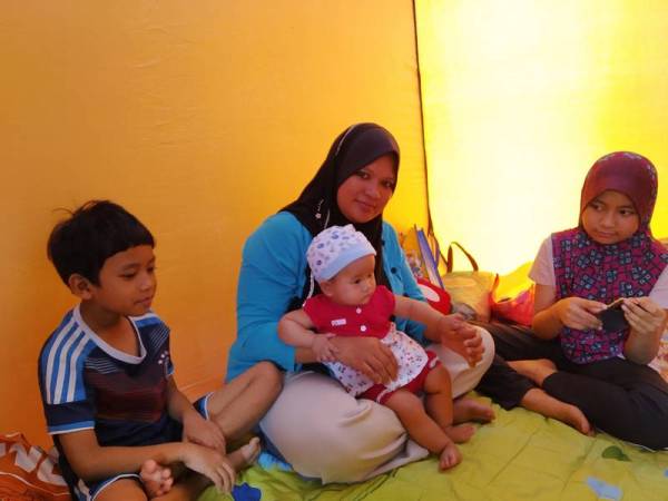 Siti Khadijah memangku anaknya berusia enam bulan di PPS Kampung Sawah Pekan Nanas.