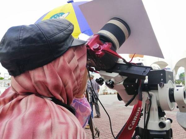 Penolong Pegawai Hal Ehwal Islam Bahagian Falak Jabatan Mufti Perak, Fatimah Ayoub menggunakan kamera digital untuk melihat gerhana matahari separa di pekarangan Masjid Negeri di Ipoh hari ini.