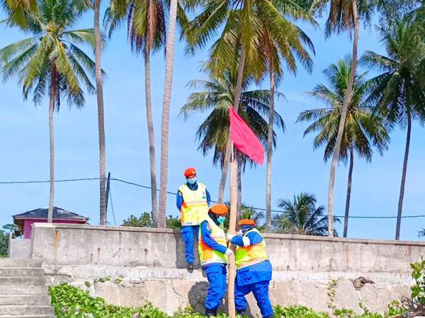 Anggota APM Pasir Puteh menaikkan bendera merah supaya pengunjung menjauhi aktiviti mandi-manda di kawasan itu.
