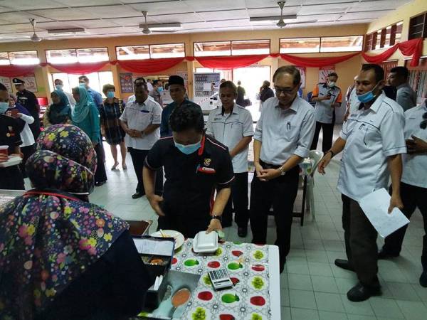 Hang Soon (dua dari kanan) melihat pelajar membeli makanan di kantin.