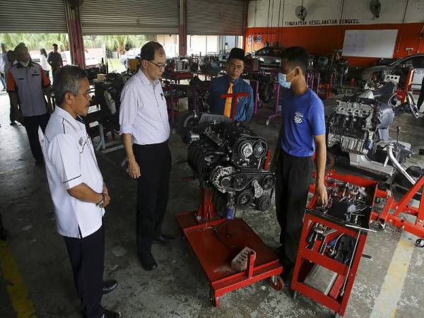 Dr Mah Hang Soon (dua, kiri) mendengar penerangan daripada pelajar Diploma Teknologi Automotif Muhammad Adib Ahmad Razif (kanan) mengenai membaik pulih enjin kereta semasa meninjau di bengkel kenderaan ketika tinjauan hari pertama pembukaan semula sekolah pasca Perintah Kawalan Pergerakan (PKP) di Kolej Vokasional Ampangan hari ini.- Foto Bernama